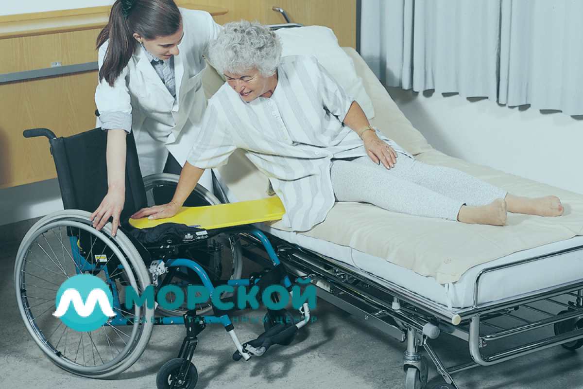 Медсестра помогает бабушке сесть на коляску