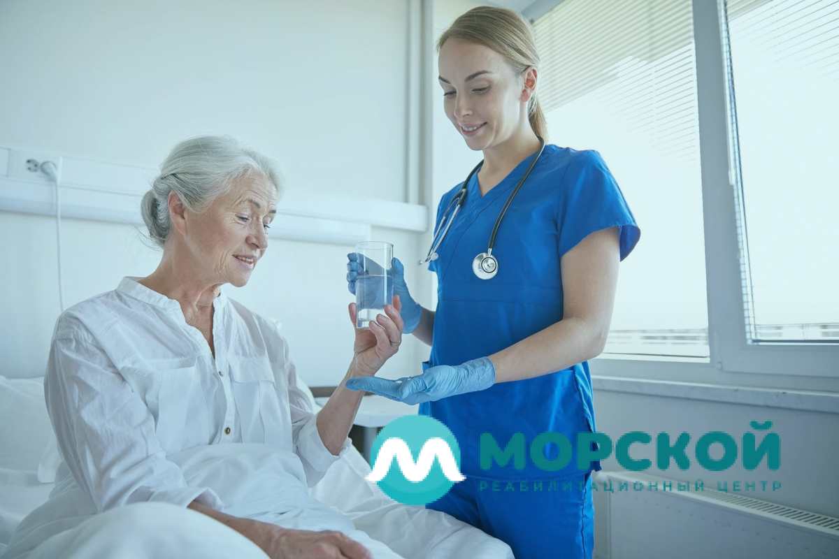 Медсестра даёт стакан воды бабушке